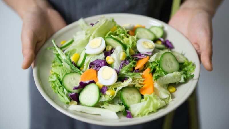 a person holding a plate of salad