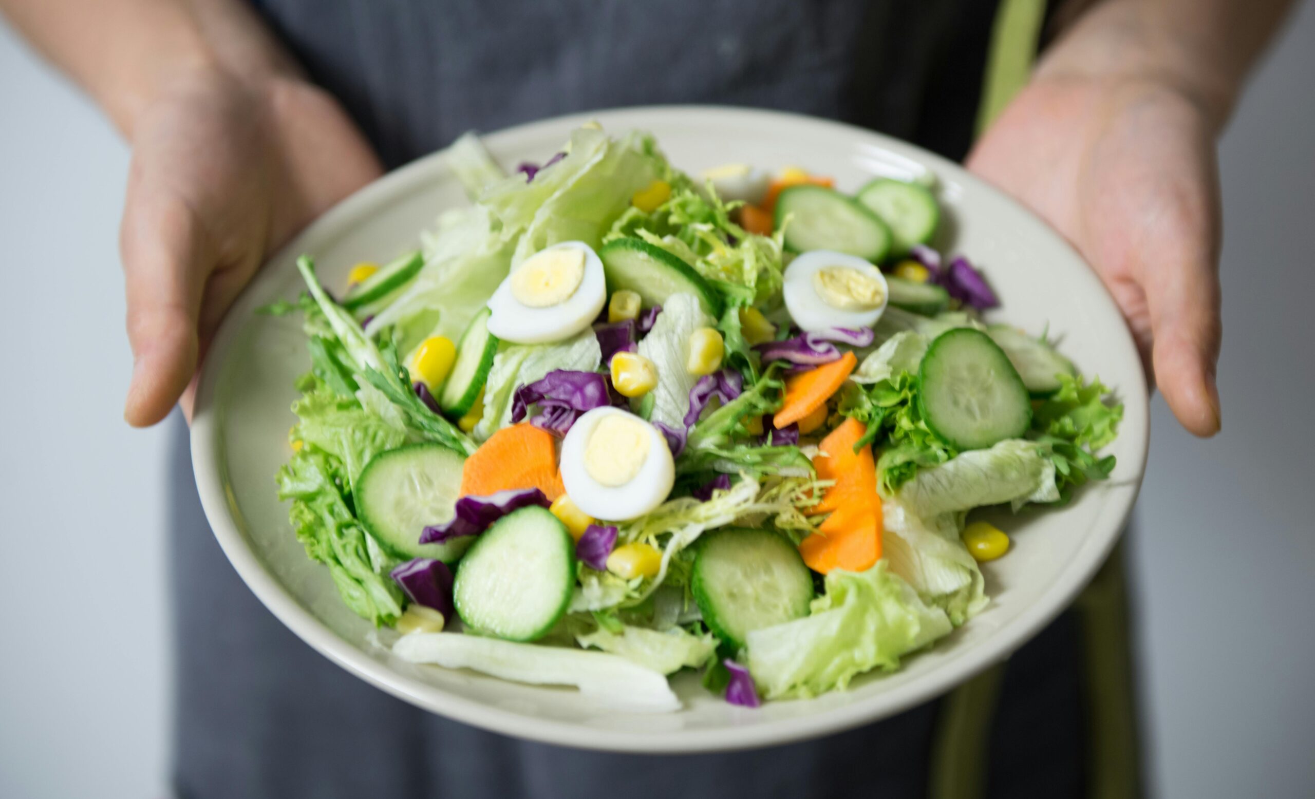 a person holding a plate of salad