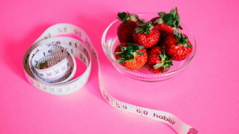 a bowl of strawberries and a measuring tape