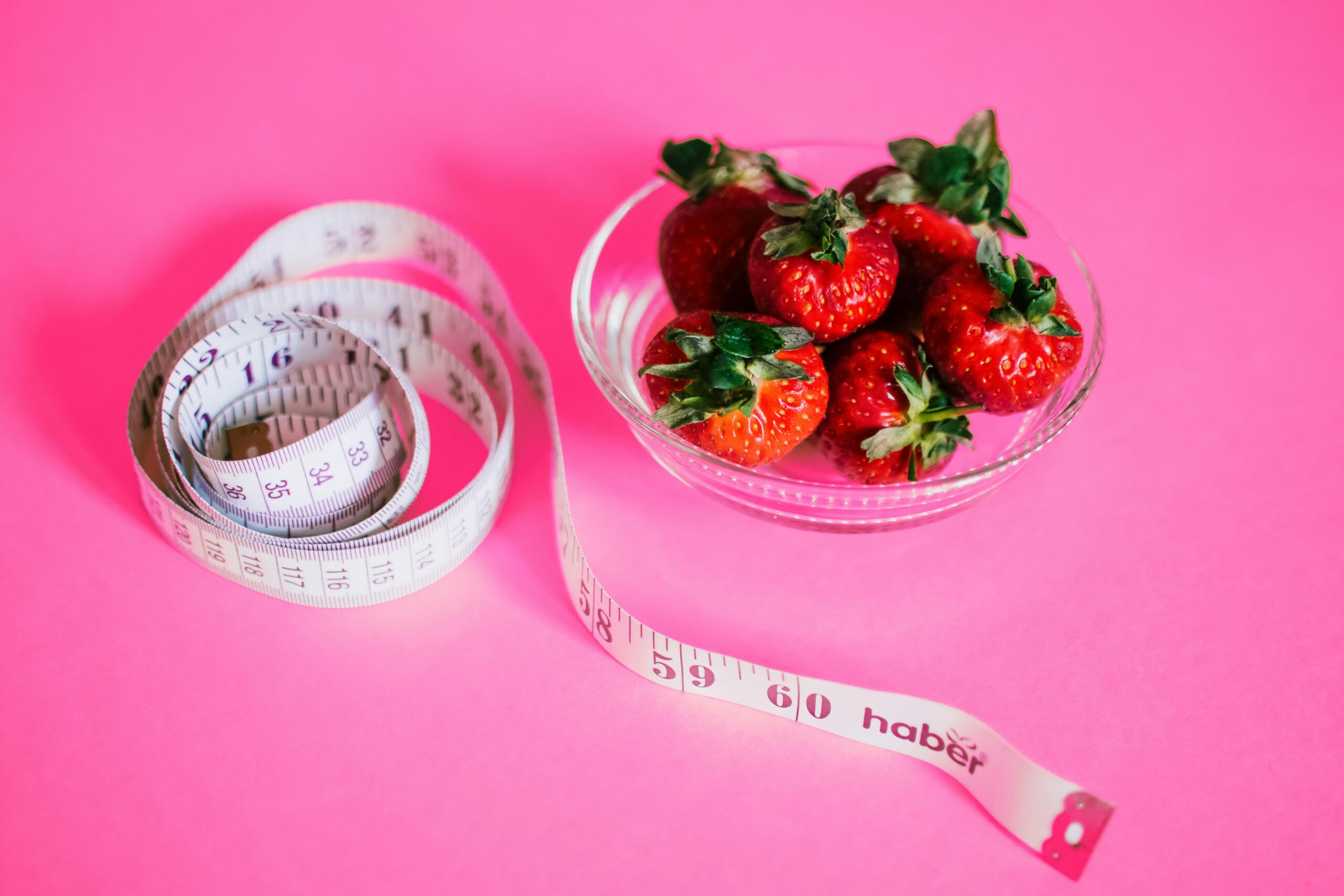 a bowl of strawberries and a measuring tape