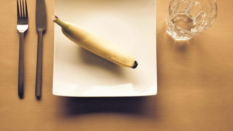 a banana on a plate with a fork and knife